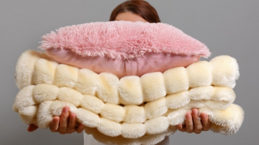 woman-holding-stack-warm-fluffy-plaid-pillow_111863-209